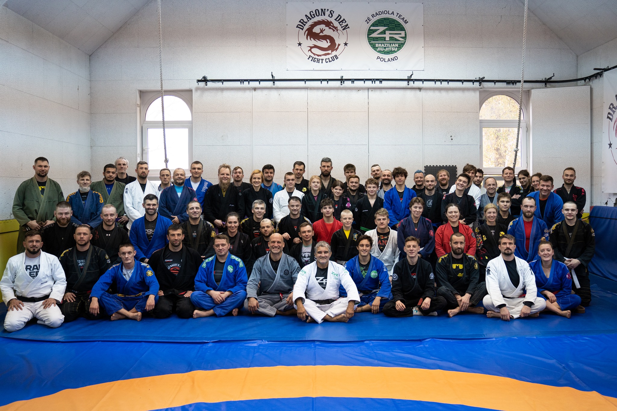 BJJ team seating at the platform holding medals and trophies