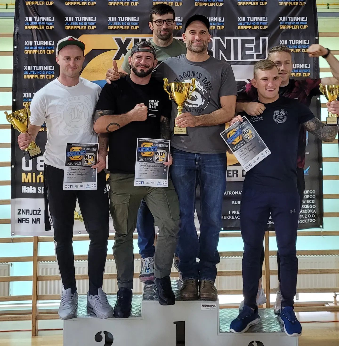 BJJ team seating at the platform holding medals and trophies